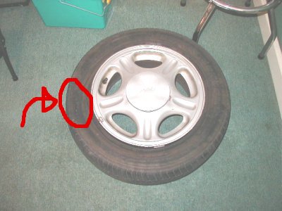 1997 Ford Taurus - A tire is shown on the floor, with a red arrow pointing to a circled area on its sidewall.