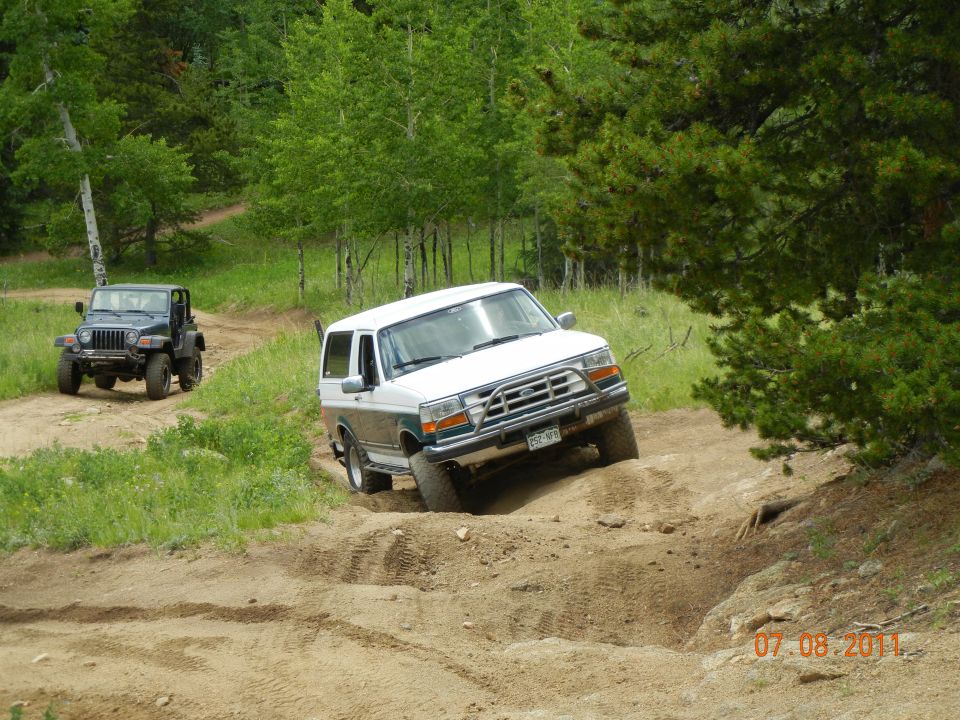 White and green 1996 Ford Bronco on a dirt trail, 3q-front view