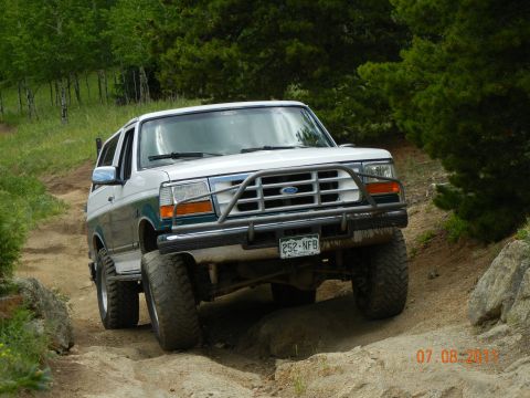 1996 Ford Bronco - A two-tone Ford Bronco navigates a rocky off-road path.