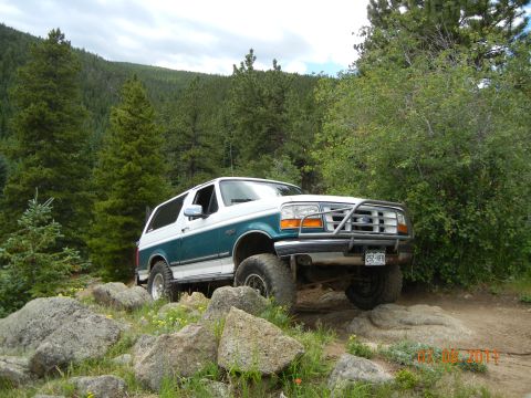 1996 Ford Bronco - This 1996 Ford Bronco navigates a challenging rocky path surrounded by trees.