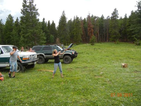 1996 Ford Bronco - People are gathered in a field with two SUVs, with one woman practicing with a rifle.