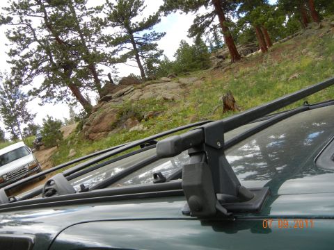 1996 Ford Bronco - A green Ford Bronco is parked on a dirt road with trees and rocks in the background.