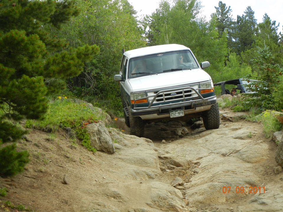 1996 Ford Bronco navigating a rocky trail, with another vehicle visible behind it