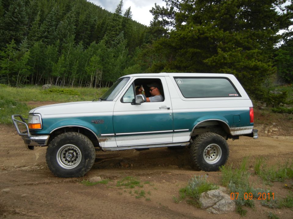 1996 Ford Bronco on a dirt road with trees in background