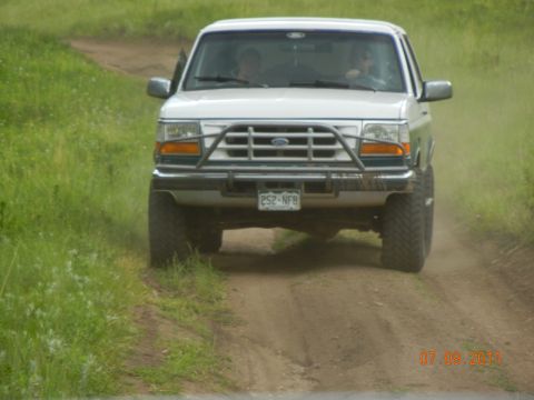 1996 Ford Bronco - This 1996 Ford Bronco is captured from the front as it drives along a dusty, unpaved road.