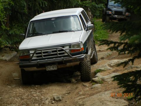 1996 Ford Bronco - A 1996 Ford Bronco navigates a challenging off-road trail with another vehicle visible in the background.