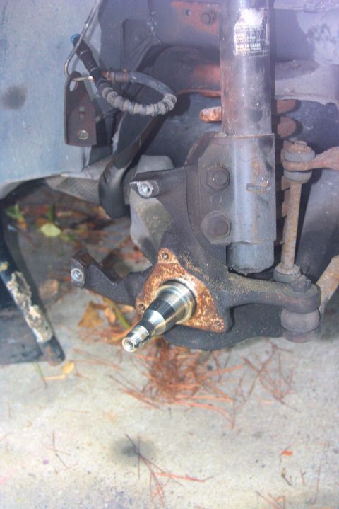 1980 Ford Mustang - Close-up view of a vehicle's front suspension spindle and brake component, likely undergoing maintenance.