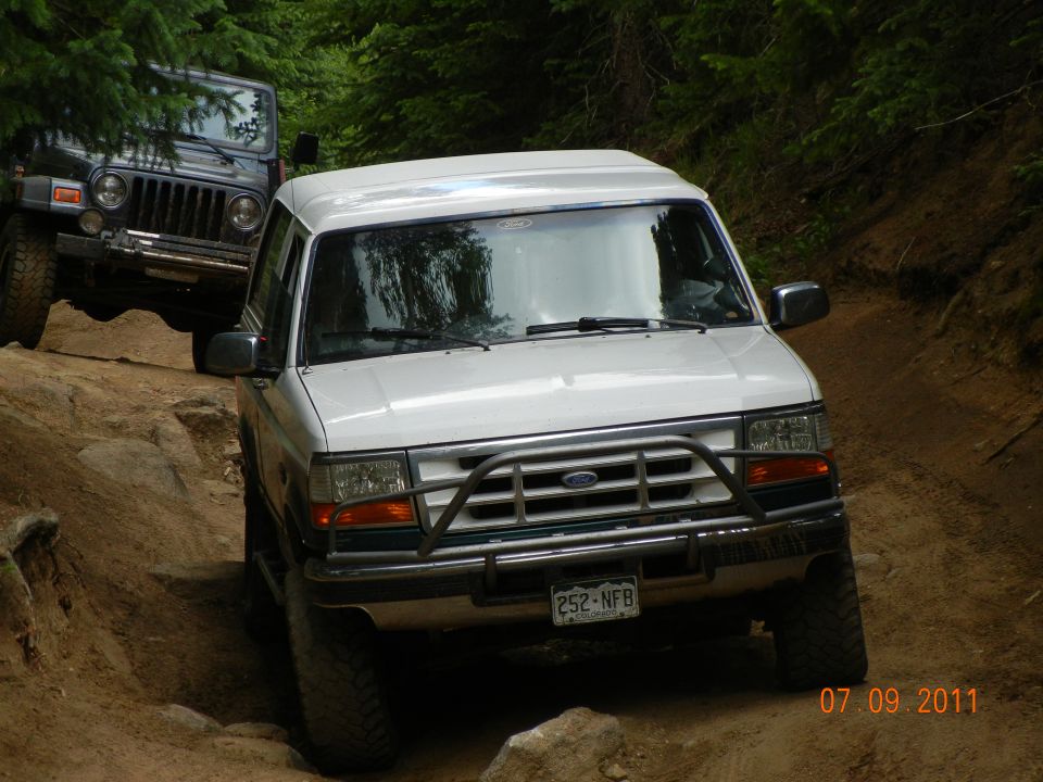 1996 Ford Bronco and Jeep Wrangler driving on a rocky dirt trail