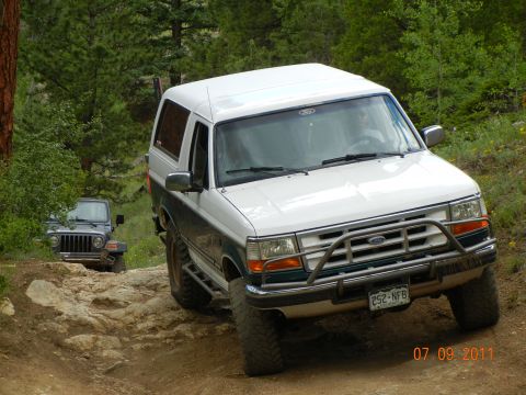 1996 Ford Bronco - A 1996 Ford Bronco navigates a rocky off-road trail, with a Jeep following closely behind.