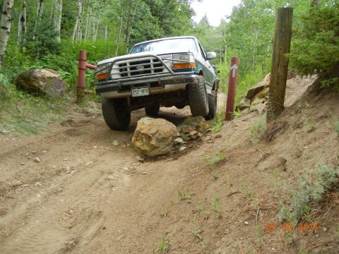 1996 Ford Bronco - A 1996 Ford Bronco navigates a challenging off-road path with large rocks.