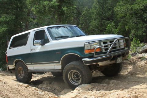 1996 Ford Bronco - A two-tone 1996 Ford Bronco navigates a challenging off-road path.