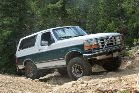 1996 Ford Bronco - This two-tone 1996 Ford Bronco navigates a challenging off-road trail with steep inclines and loose rocks.