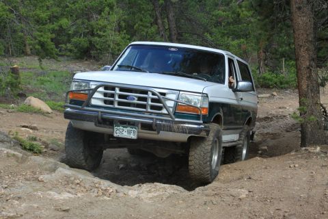 1996 Ford Bronco - This two-tone Ford Bronco navigates a rocky, wooded trail with a brush guard on the front.
