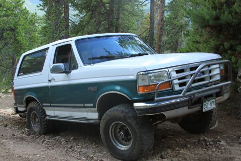 1996 Ford Bronco - This 1996 Ford Bronco is equipped with a brush guard and is navigating a dirt trail in a wooded area.