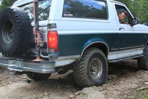 1996 Ford Bronco - A man looks out the window of a Ford Bronco as it navigates a rocky off-road trail.