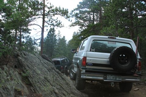 1996 Ford Bronco - A silver Ford Bronco navigates a rocky trail with another SUV following behind.