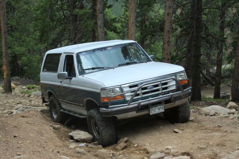 1996 Ford Bronco - Ford Bronco tackles a challenging off-road path through a forest.