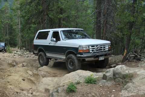1996 Ford Bronco - This 1996 Ford Bronco is shown tackling a challenging off-road path through a wooded area.
