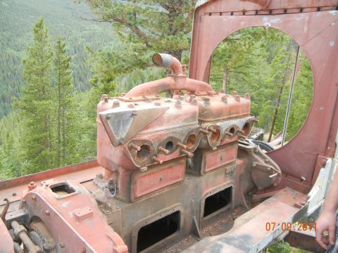 1996 Ford Bronco - Engine block detail with exhaust manifold and piping visible, set in a wooded area.