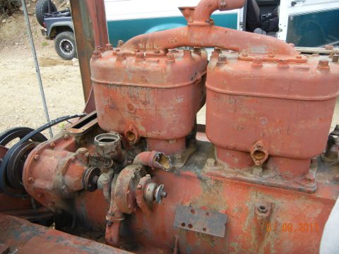 1996 Ford Bronco - This is a close-up of an old, rusty industrial engine. A dark SUV is visible in the background.