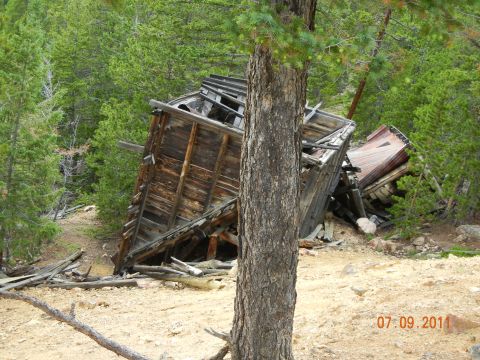 1996 Ford Bronco - An old wooden building has fallen into disrepair in a wooded area.