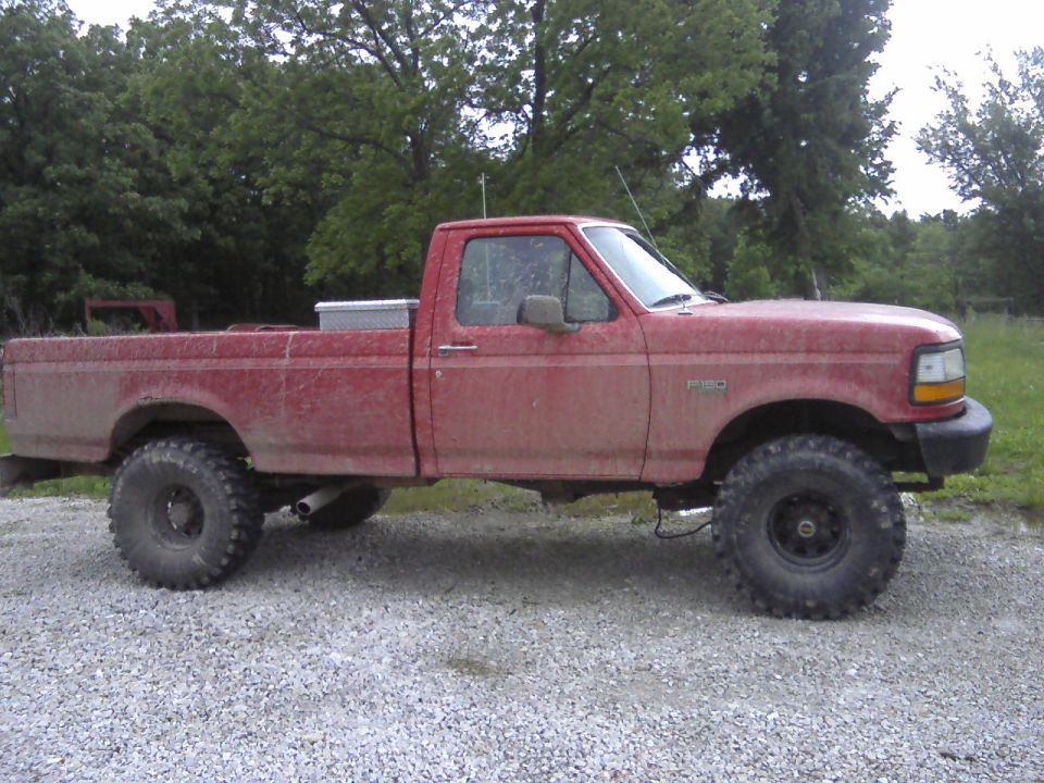 Red 1995 Ford F-150 side view with lifted suspension and large tires