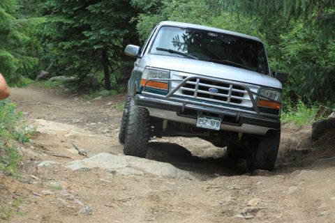 1996 Ford Bronco - This 1996 Ford Bronco is tackling a challenging off-road path in a wooded area.