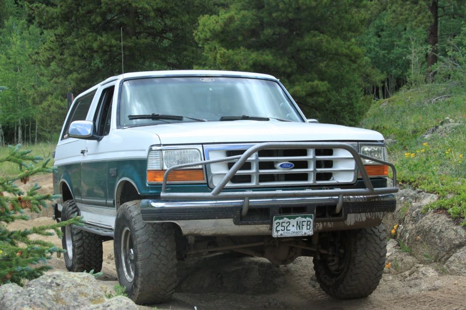 White and green Ford Bronco with a brush guard on a rocky trail