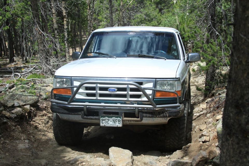 White 1996 Ford Bronco on a rocky trail, front view