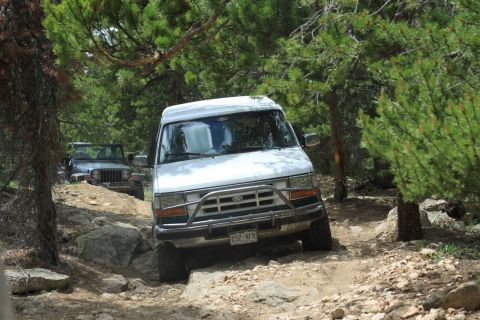 1996 Ford Bronco - A white van navigates a challenging off-road path with a Jeep in the background.