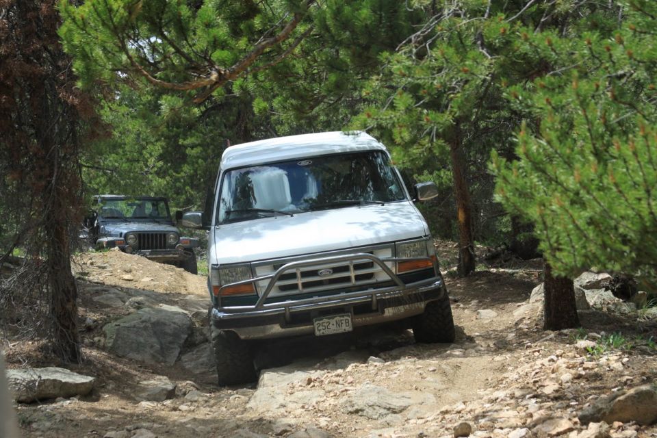 White van with a brush guard driving on a rocky trail