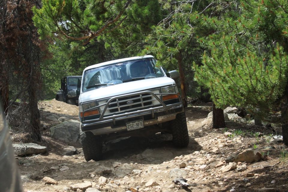 White 1996 Ford Bronco on rocky trail with another vehicle behind