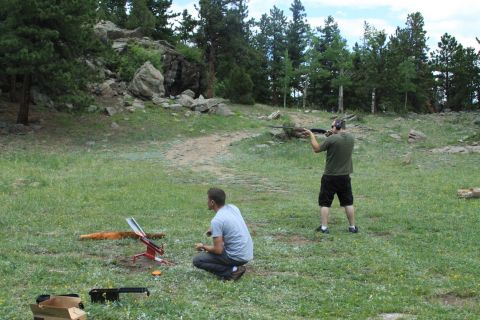 1996 Ford Bronco - Two men are engaged in shooting clay pigeons in a natural outdoor setting with trees and rocks.