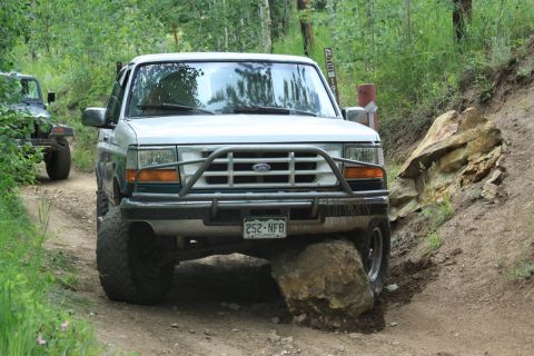 1996 Ford Bronco - A white Ford Bronco navigates a rocky trail with another vehicle visible behind it.