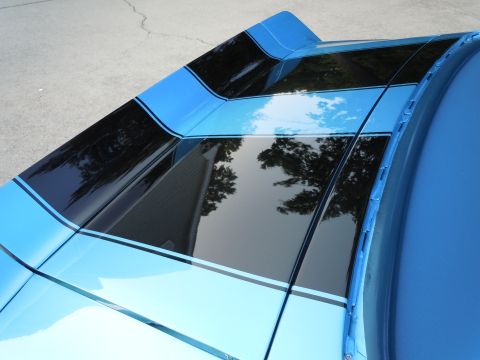 1972 Chevrolet Camaro - The glossy finish of the car's roof reflects the surrounding environment, including trees and a building.