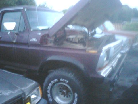 1988 Ford Bronco - A maroon Ford truck, likely from the late 1970s, has its hood up, revealing the engine compartment.