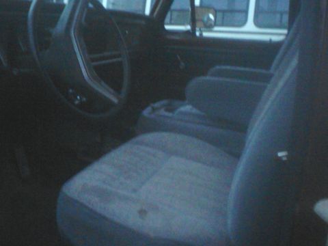 1988 Ford Bronco - The interior of a vehicle shows the driver's seat, passenger seat, and steering wheel.