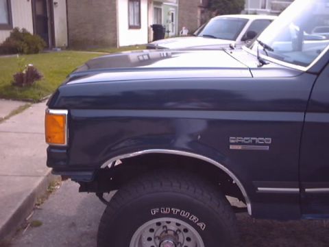 1990 Ford Bronco - Close-up of a 1990 Ford Bronco's side, highlighting the fender, wheel, and "Bronco" badging.