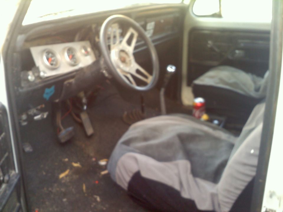 Interior of a vehicle with aftermarket gauges, a custom steering wheel, and seat covers