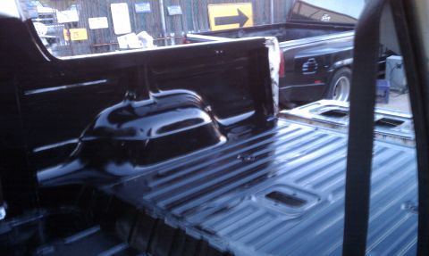 1978 Ford Bronco - The ribbed metal floor of a black pickup truck bed is shown, with another truck in the background.