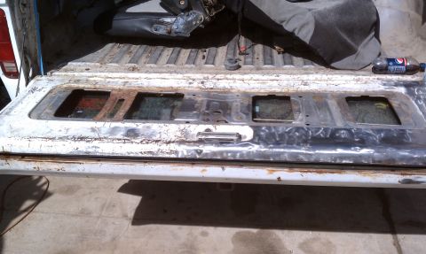 1978 Ford Bronco - The interior of a tailgate shows signs of wear and tear, with rusted metal and missing glass panels.