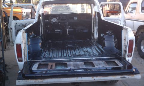 1978 Ford Bronco - The interior and bed of a white Ford pickup truck are shown, with other vehicles in the background.