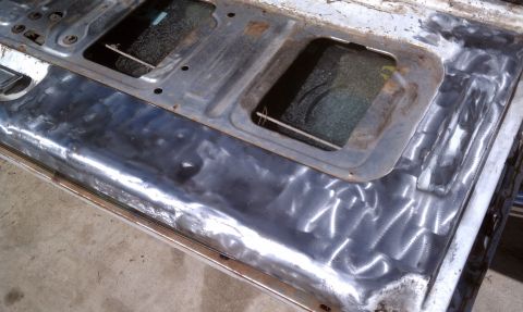 1978 Ford Bronco - Interior panel stripped to bare metal, revealing grinding marks and two small windows.