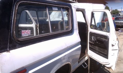 1978 Ford Bronco - Interior view of a 1978 Ford Bronco, showing the driver's side door open and a glimpse of another vehicle outside.