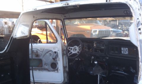 1978 Ford Bronco - Interior view of a white truck, showing the dashboard and door panel. Another vehicle is visible through the windshield.