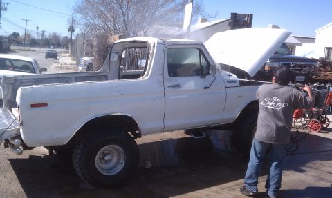 1978 Ford Bronco - A person is pressure washing a white Ford Bronco with its hood open.
