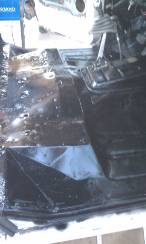 1978 Ford Bronco - The interior floor of a vehicle is shown after being painted black, with water droplets present.