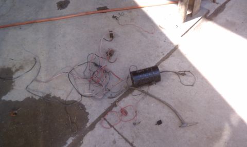 1978 Ford Bronco - A collection of vehicle wiring and a black cylindrical part are spread out on a concrete surface.