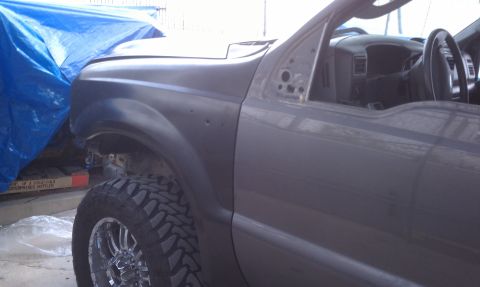 1978 Ford Bronco - Interior view of a gray truck, showing the dashboard and door frame, with a large off-road tire visible.