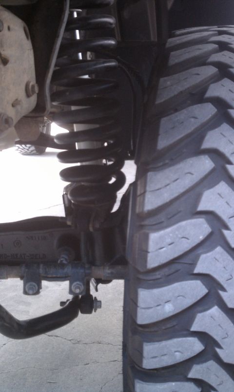 1978 Ford Bronco - Detail of a vehicle's suspension system and tire tread.